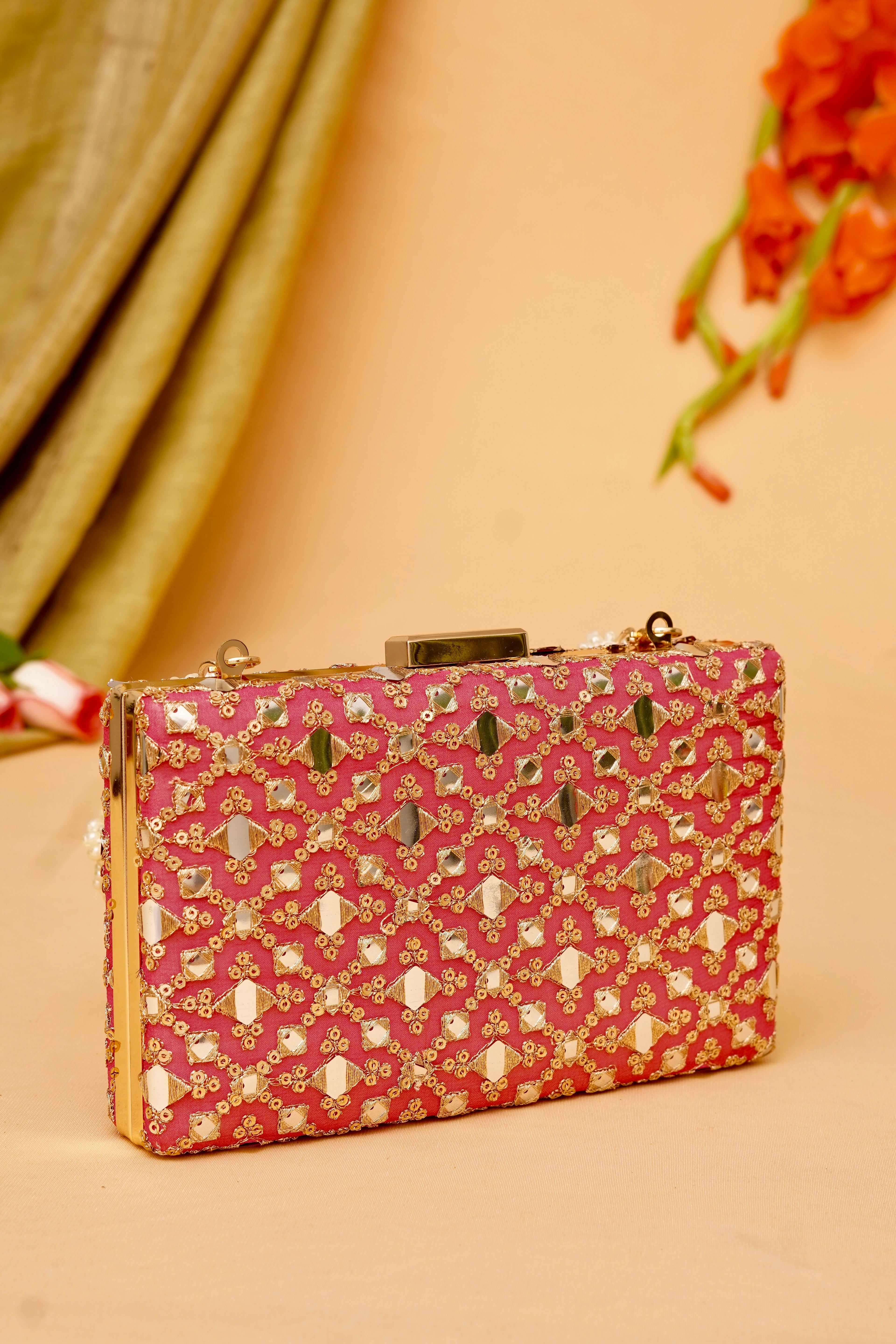 Pink clutch bag with decorative patterns on a beige background