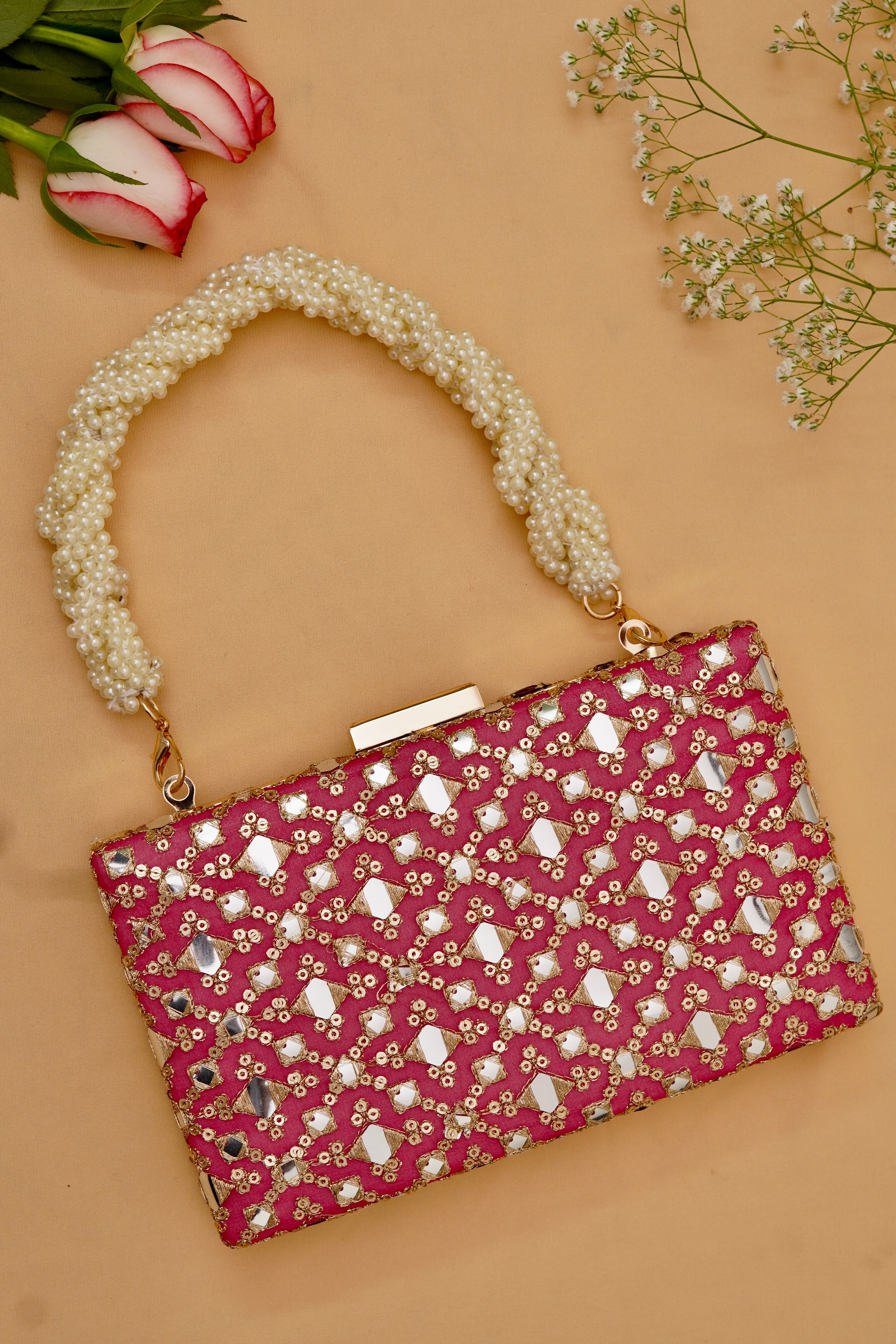 Pink clutch bag with pearl handle on a beige background