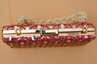 Pink clutch with gold accents and pearl chain on a beige background