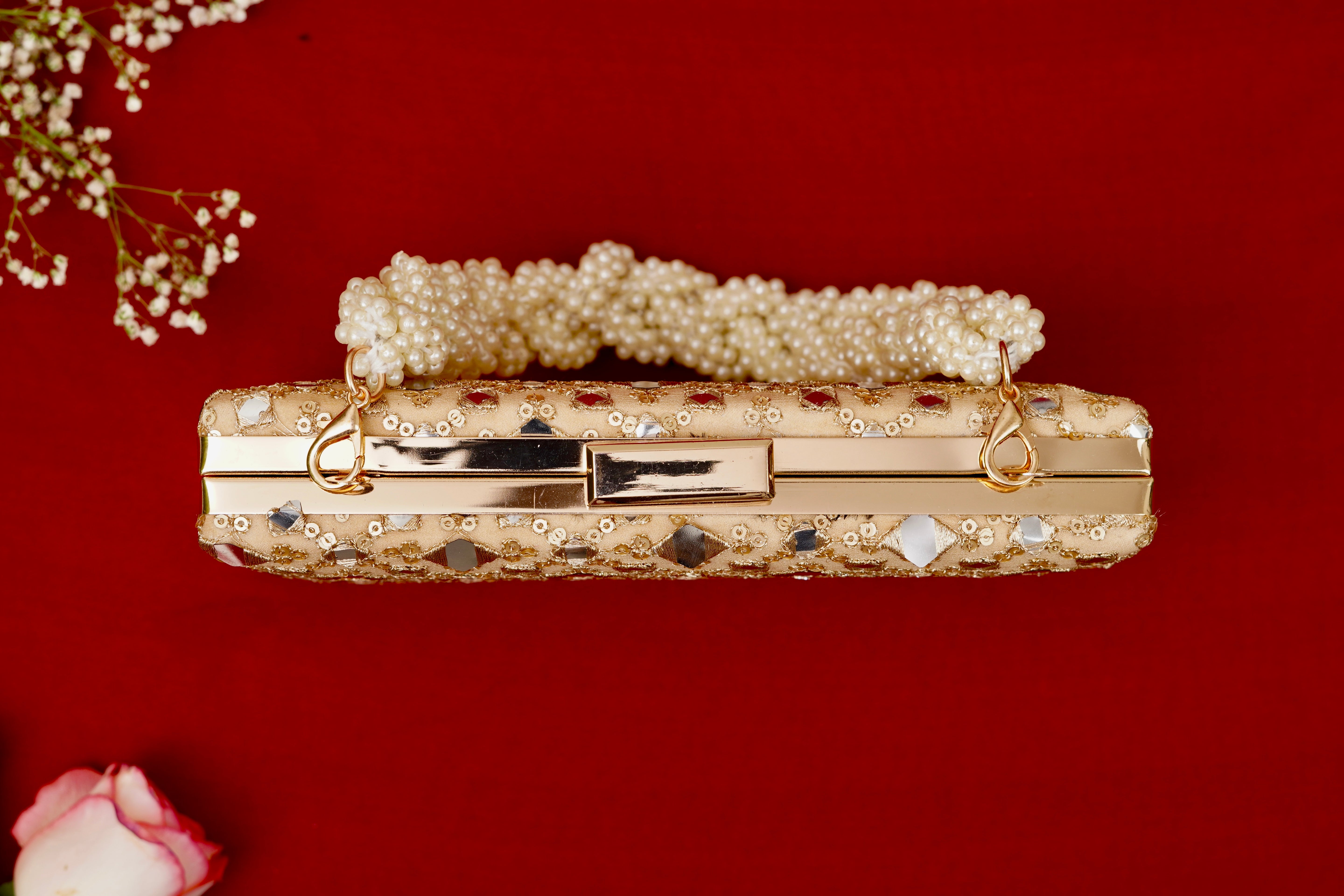Gold clutch with pearl handle on a red background